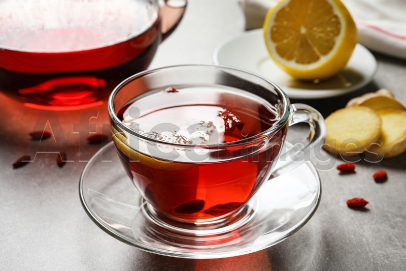 Glass cup of healthy goji tea with lemon on grey table