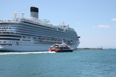 Modern cruise ship and boat in sea on sunny day