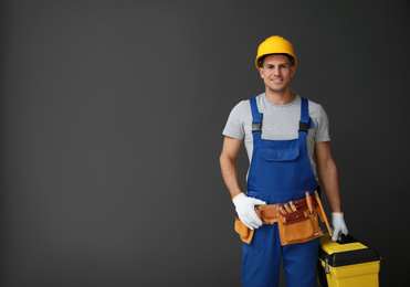 Handsome carpenter with tool box on dark background. Space for text