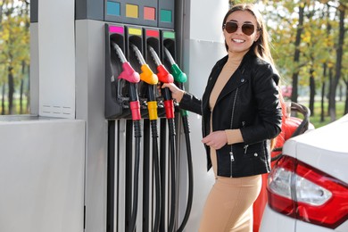 Woman taking fuel pump nozzle at self service gas station