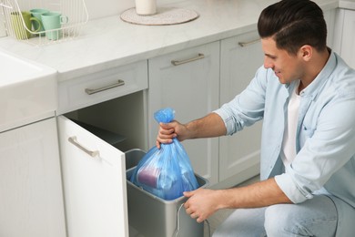 Man taking garbage bag out of bin at home