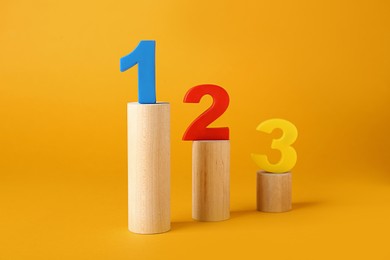 Photo of Numbers on wooden blocks against pale orange background. Competition concept