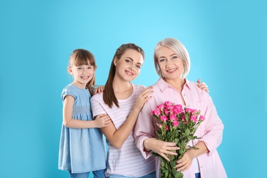 Beautiful mature lady, daughter and grandchild with flowers on color background. Happy Women's Day