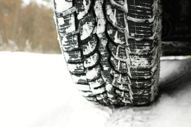 Car with winter tires on snowy road, closeup of wheel