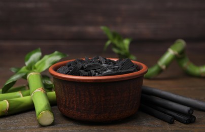 Photo of Fresh bamboo and charcoal on wooden table, closeup