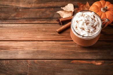 Delicious pumpkin latte on wooden table, above view. Space for text