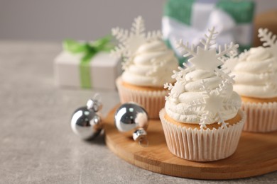 Photo of Tasty Christmas cupcakes with snowflakes on grey table. Space for text