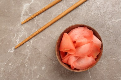 Photo of Spicy pickled ginger and chopsticks on grey table, flat lay