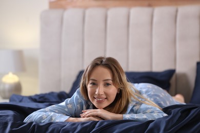 Young woman lying on comfortable bed with silky linens