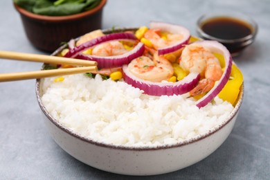 Photo of Delicious poke bowl with shrimps, rice and vegetables served on light grey table, closeup