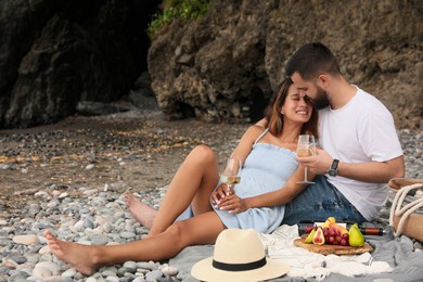 Happy young couple having picnic on beach. Space for text