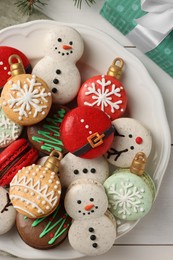Beautifully decorated Christmas macarons and gift box on white wooden table, flat lay