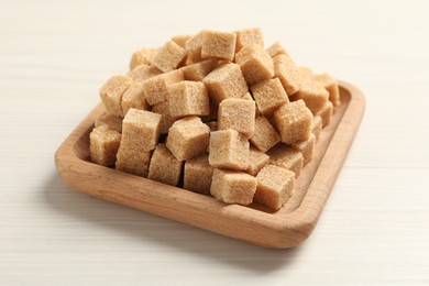 Brown sugar cubes on white wooden table