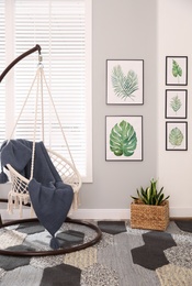 Stylish room interior with artworks and hanging chair