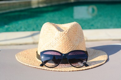 Photo of Stylish hat and sunglasses near outdoor swimming pool
