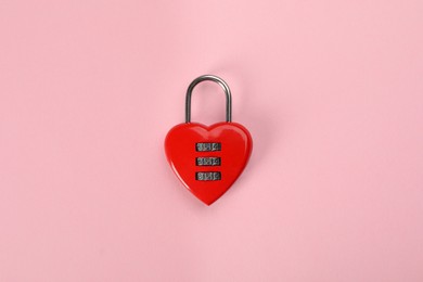 Red heart shaped combination lock on pink background, top view