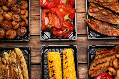 Plastic containers with different grilled meal on wooden table, flat lay. Food delivery service