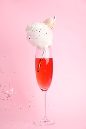 Cocktail with cotton candy in glass on pink background