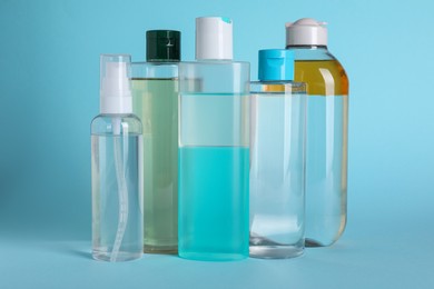 Bottles of micellar water on light blue background