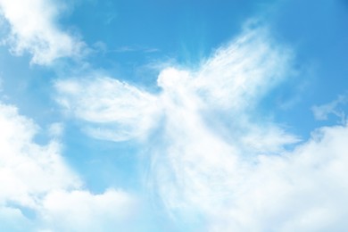 Silhouette of angel made of clouds in blue sky 