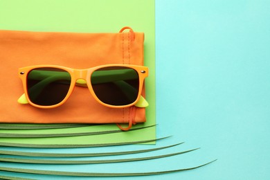 Stylish sunglasses with bag on color background, top view. Space for text