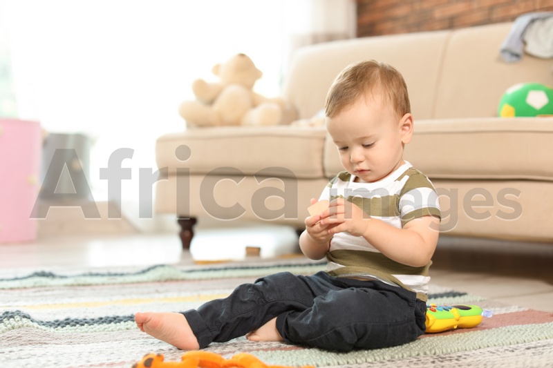 Photo of Adorable little baby sitting on floor at home