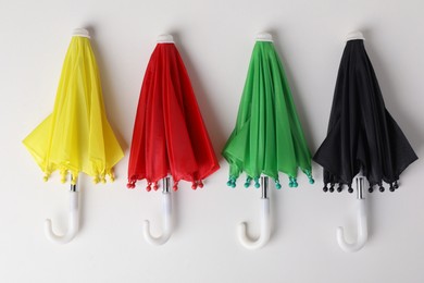 Small color umbrellas on white background, top view