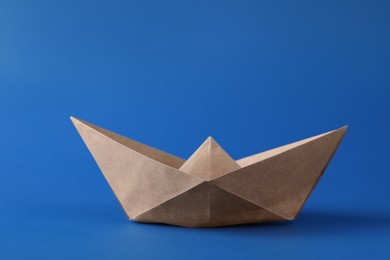 Handmade beige paper boat on blue background. Origami art
