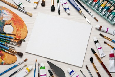 Blank canvas, brushes, paints and palette on white wooden table, flat lay. space for text