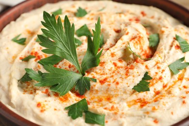 Photo of Tasty hummus with parsley and paprika in bowl, closeup