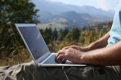 Man working with laptop outdoors on sunny day, closeup