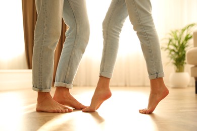 Photo of Couple dancing barefoot at home, closeup. Floor heating system