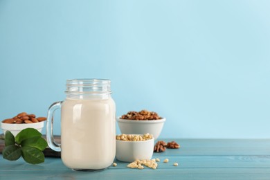 Vegan milk and different nuts on light blue wooden table. Space for text