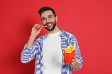 Man eating French fries on red background