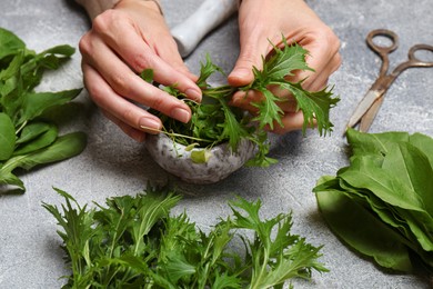 Photo of Woman with fresh green herbs at light grey table, closeup
