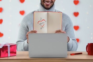 Photo of Valentine's day celebration in long distance relationship. Man having video chat with his girlfriend via laptop, closeup