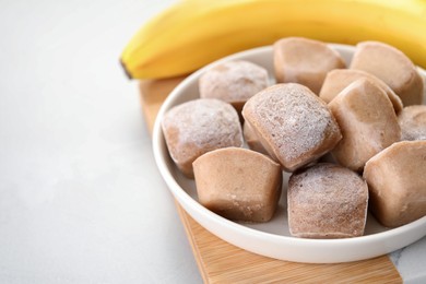 Frozen banana puree cubes and ingredient on light grey table, closeup. Space for text