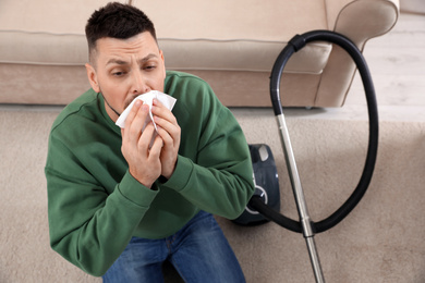 Man with vacuum cleaner suffering from dust allergy at home, above view