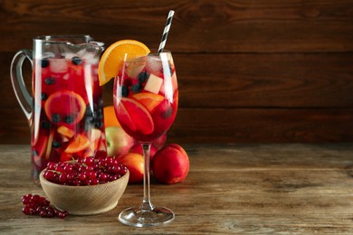 Glass and jug of Red Sangria with fruits on wooden table. Space for text
