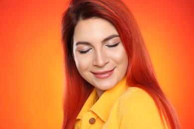 Young woman with bright dyed hair on color background