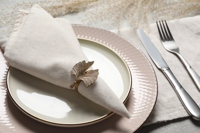 Plates with fabric napkin, decorative ring and cutlery on table