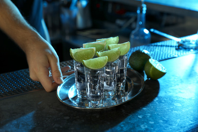 Bartender with shot glasses of Mexican Tequila at bar counter, closeup