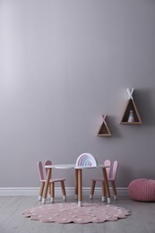 Cute child room interior with furniture, toys and wigwam shaped shelves on grey wall