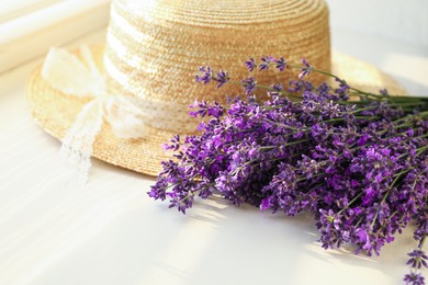 Photo of Beautiful lavender flowers and straw hat on window sill, closeup