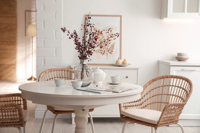 Photo of Dining room interior with tea set on round table and wicker chairs