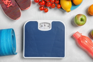 Flat lay composition with scales, healthy food and sport equipment on light background. Weight loss