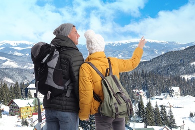 Happy couple with travel backpacks enjoying mountain landscape during vacation trip
