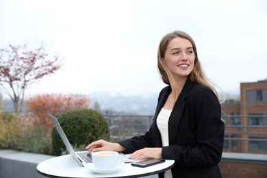 Businesswoman working with laptop in outdoor cafe. Corporate blog