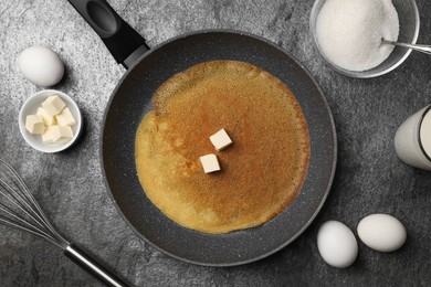 Frying pan with delicious crepe and ingredients on grey table, flat lay