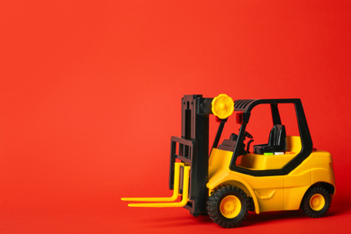 Toy forklift on red background, space for text. Logistics and wholesale concept